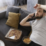 young-man-eating-junk-food-home-sofa